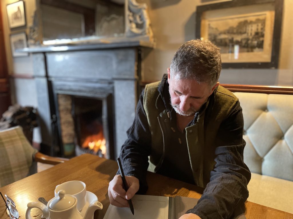 Gerard Collins writing by a cozy fire